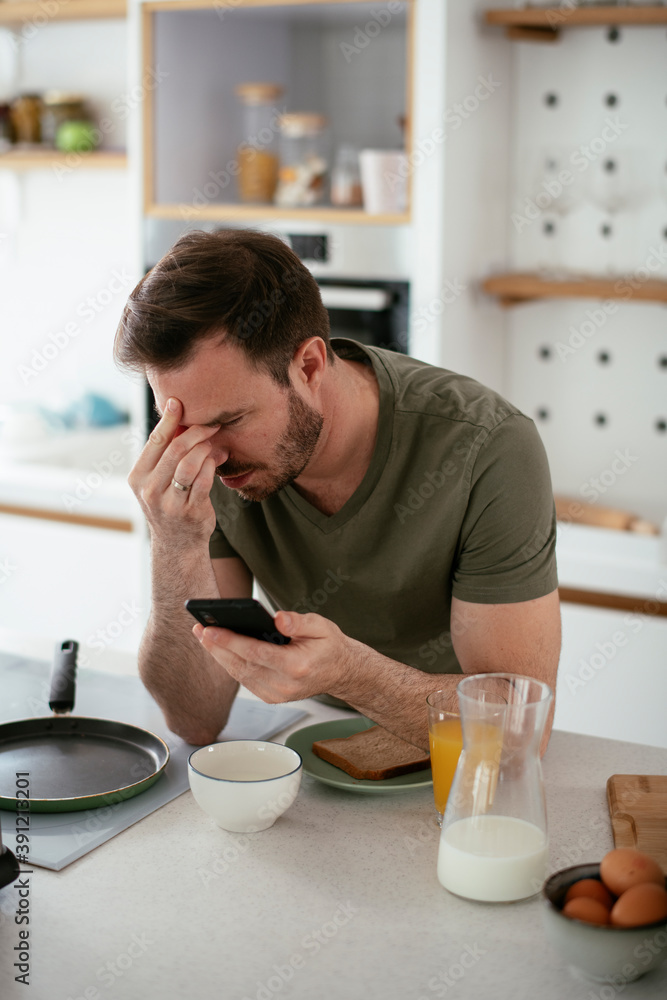 Young man eating breakfast and reading the news online. Handsome man enjoying at home. Young man eating breakfast and reading the news online. Handsome man enjoying at home.