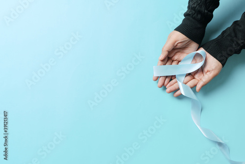 November light blue ribbon on woman hand with copy space, Prostate cancer awareness month, men's health concept photo