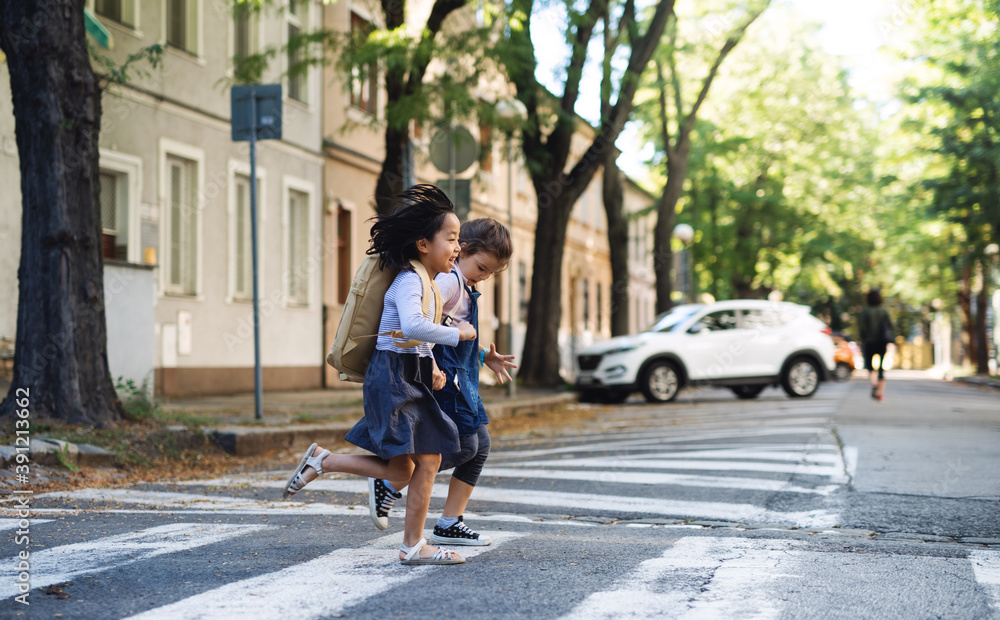 Small girls crossing street outdoors in town, coronavirus concept.