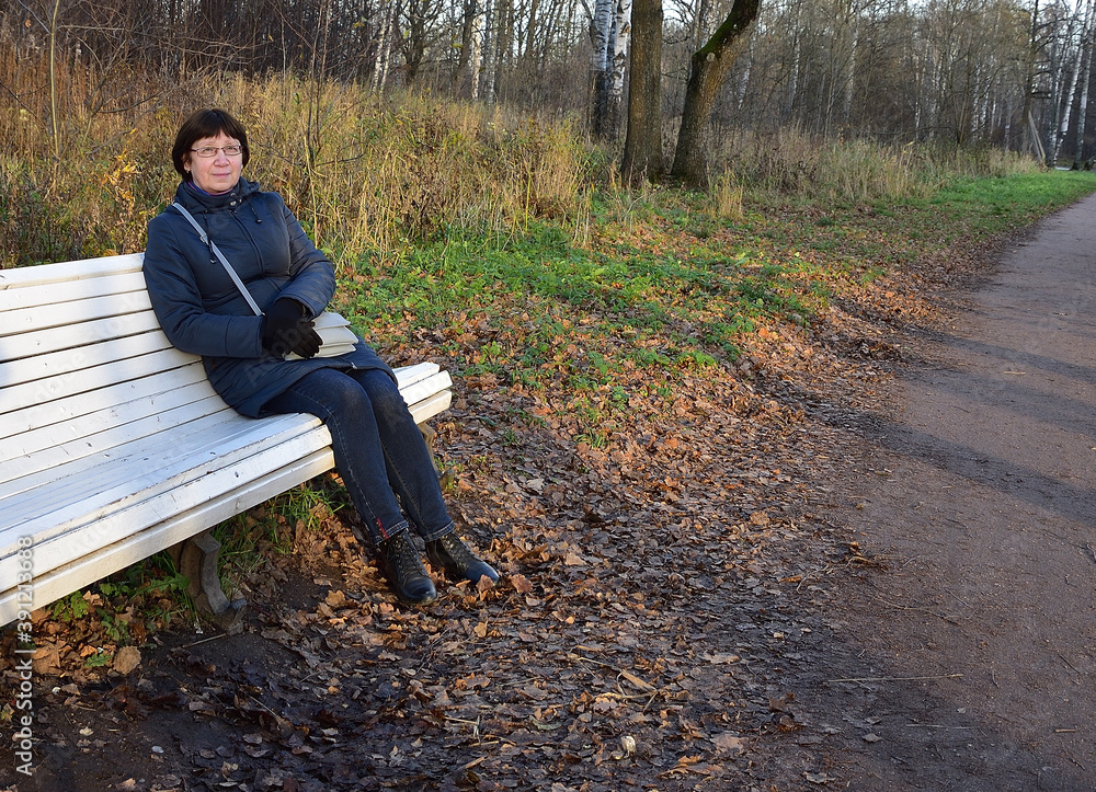 Fototapeta premium After a long walk, Natalia sat down to rest on a white bench in the park, free of strangers. 