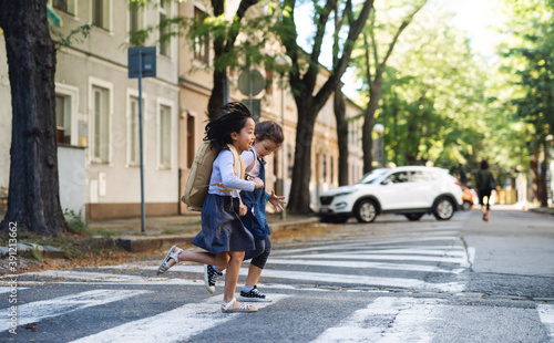 Small girls crossing street outdoors in town, coronavirus concept.