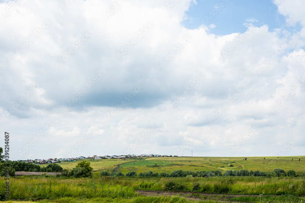 Beautiful rural landscape, village on a green hill and cloudy blue sky. Nature country life Beautiful rural landscape, village on a green hill and cloudy blue sky. Nature country life