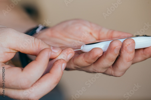 diabetes  healthcare - close up of a man with a glucometer and a test strip checking blood sugar at home