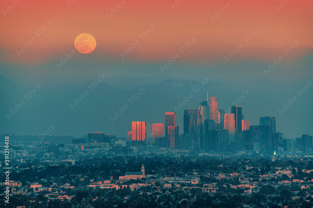 Full moon rising above downtown Los Angeles skyline background.