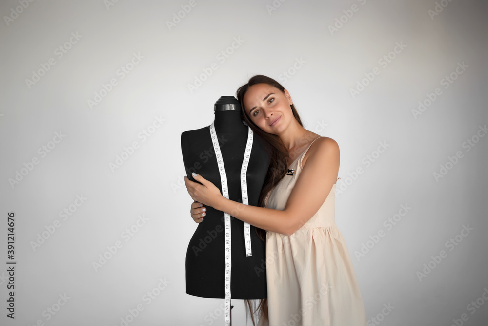 young beautiful seamstress hugs a manikin at her workplace young beautiful seamstress hugs a manikin at her workplace