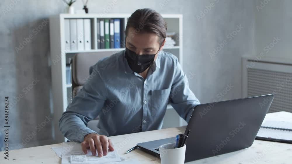Business persons is work alone in modern office using computer technology. Man in protective mask. Workplace of young businessman. Business persons is work alone in modern office using computer technology. Man in protective mask. Workplace of young businessman.