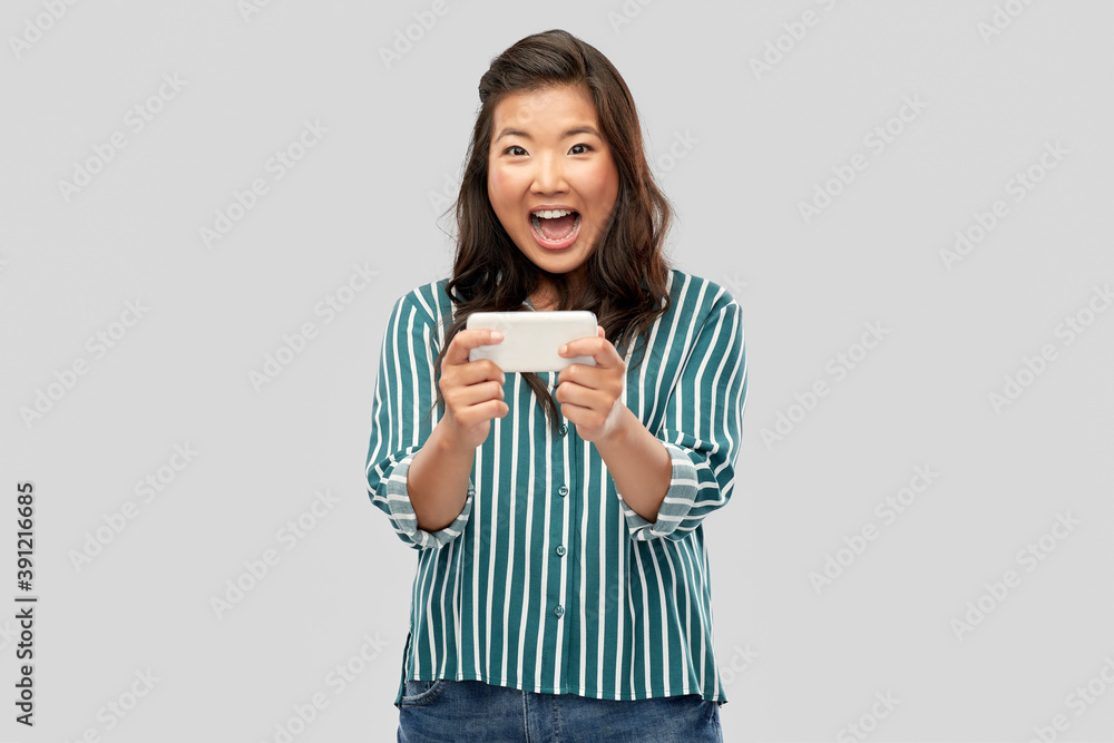 technology and people concept - happy asian woman using smartphone over grey background technology and people concept - happy asian woman using smartphone over grey background