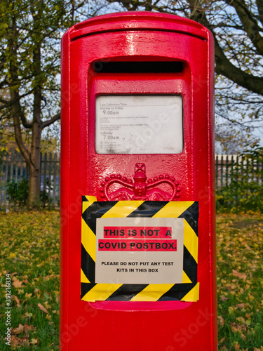Wallpaper Mural A red UK post box with a sign advising that the box should not be used for mailing COVID test kits. Torontodigital.ca