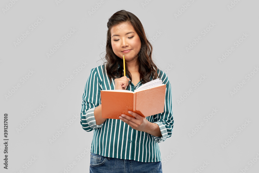 Obraz premium education, school and inspiration concept - asian student woman with diary and pencil over grey background