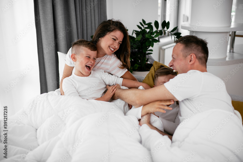 Young family enjoying in bed. Happy parents with sons relaxing in bed...