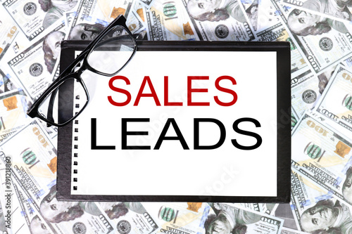 Businesales leads. text on white paper over money backgroundss man pointing the text: Sales Leads photo