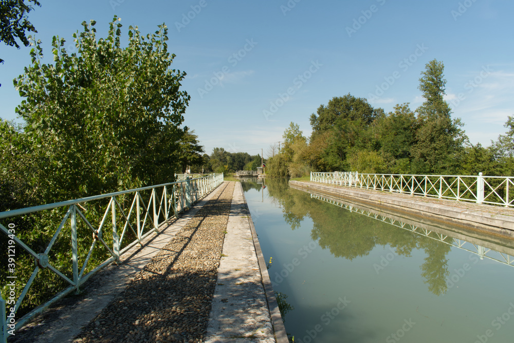 Naklejka premium Magnifique perspective pour ce pont canal sur le Canal Latéral à la Garonne où les arbres se reflètent dans l'eau