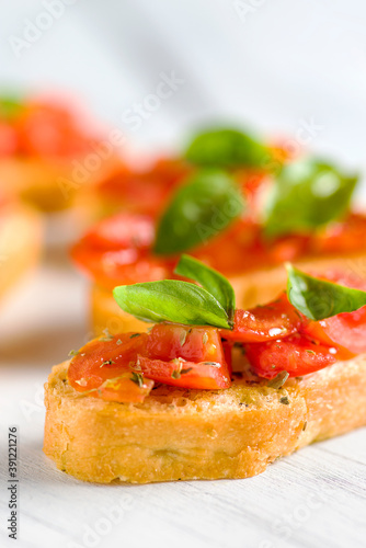Detail of bruschetta: traditional italian appetizer with tomatoes, basil leaves and olive oil.