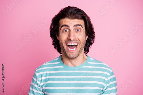 Photo portrait of amazed man smiling with opened mouth wearing blue striped t-shirt staring isolated on pastel pink color background © deagreez