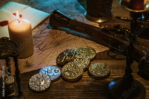 Pirate gold silver coins on old wood table with map pistol candles hourglass landscape format