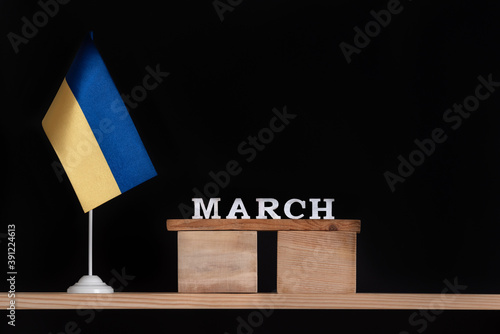 Wooden calendar of March with Ukrainian flag on black background. Dates in Ukraine in March