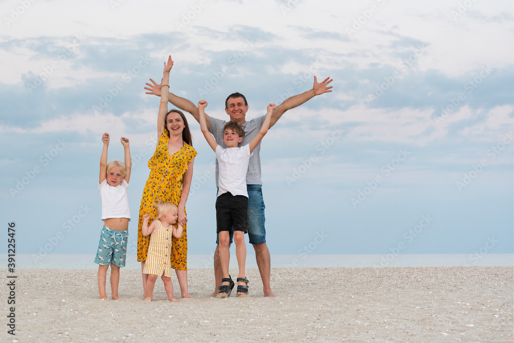 Portrait of happy family on sea beach background. Parents and three children. Family lifestyle