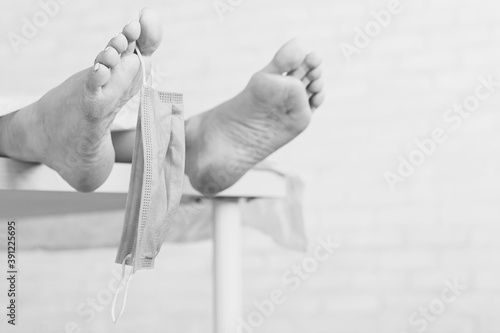 Feet of a dead woman in a morgue with a mask. Victim of the coronavirus epidemic.