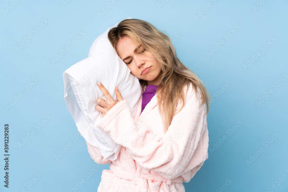 Teenager Russian girl in pajamas isolated on blue background Teenager Russian girl in pajamas isolated on blue background