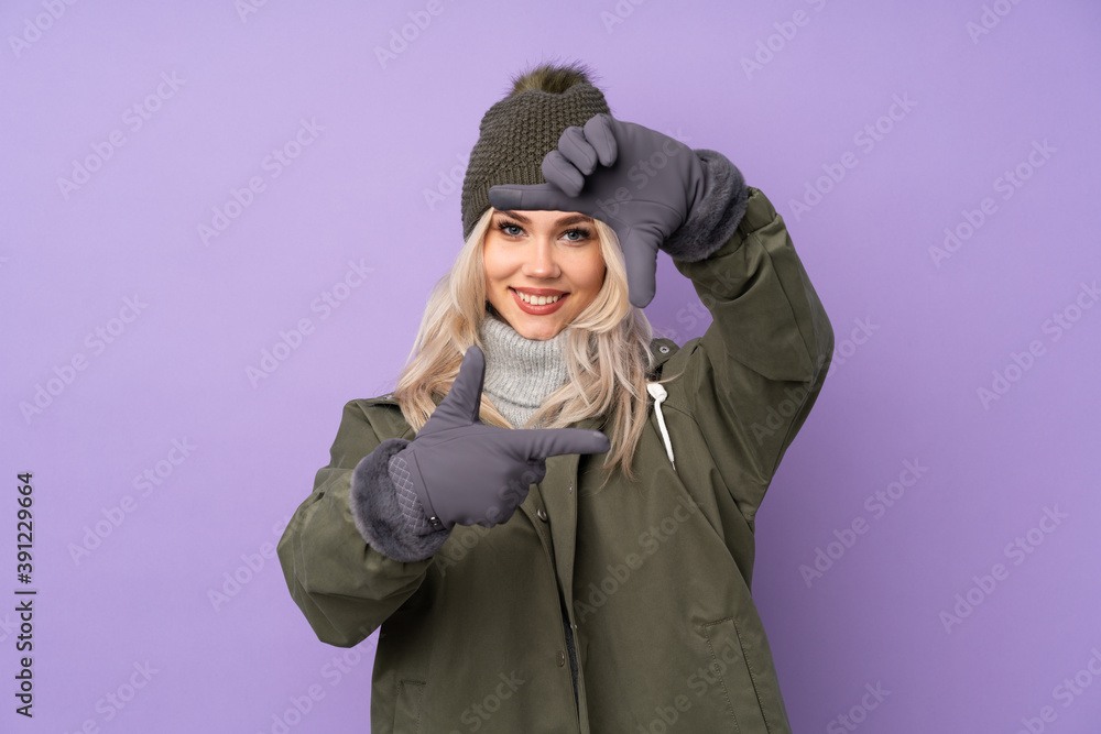 Teenager blonde girl with winter hat over isolated purple background focusing face. Framing symbol Teenager blonde girl with winter hat over isolated purple background focusing face. Framing symbol