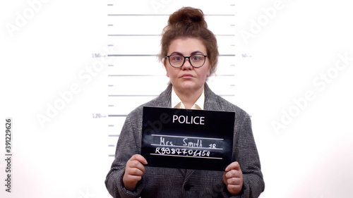 Arrested businesswoman posing for mugshot holding a signboard photo