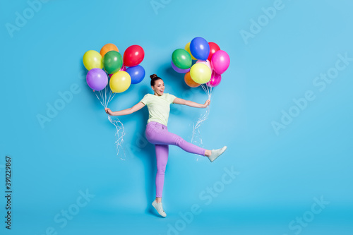 Full length body size photo of funny girl jumping keeping air balloons dancing laughing isolated on bright blue color background