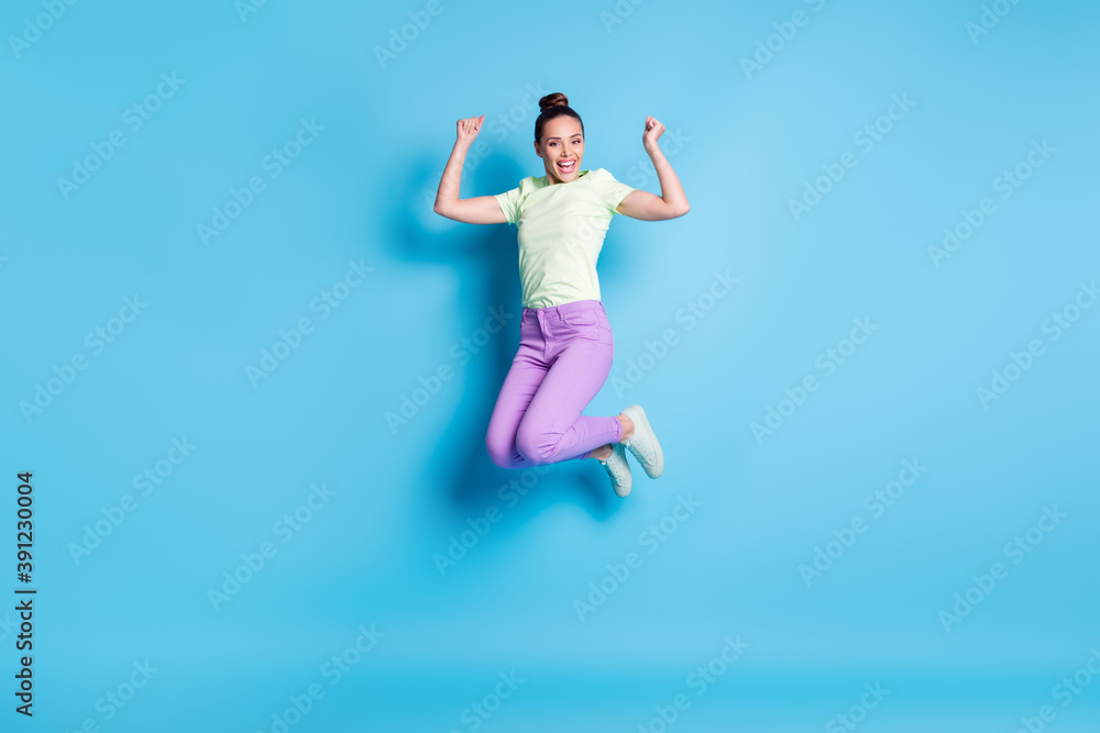 Fototapeta premium Full length body size photo of pretty girl jumping high laughing showing strong arms smiling isolated on vibrant blue color background