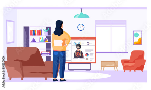 Woman is standing in the room near tv and watching video about virus covid-19 and its prevention. Online learning with a video about the need to prevent the spread of coronavirus. Stay at home