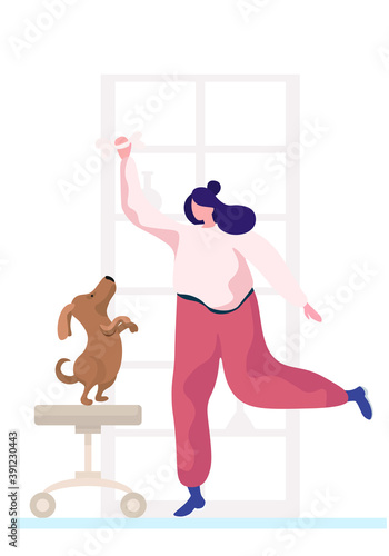 Young woman is training the animal at home. The dog is standing on its hind legs. Trainer holding bone in her hands. Rehearsal with a pet in the apartment. Puppy stands on a stool looks at the bone