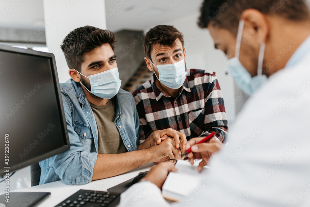 Gay couple with protective face masks together visiting doctor. Homosexuality. Pandemic, Covid
