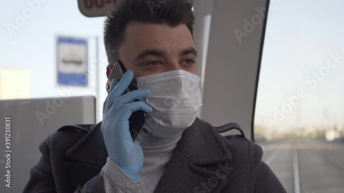 Young man in medical masc talk by his mobile phone on public transport during pandemic covid-19 coronavirus quarantine. Keep yourself and others safety. photo