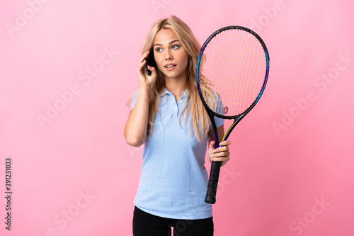 Young Russian woman playing tennis isolated on purple background keeping a conversation with the mobile phone © luismolinero