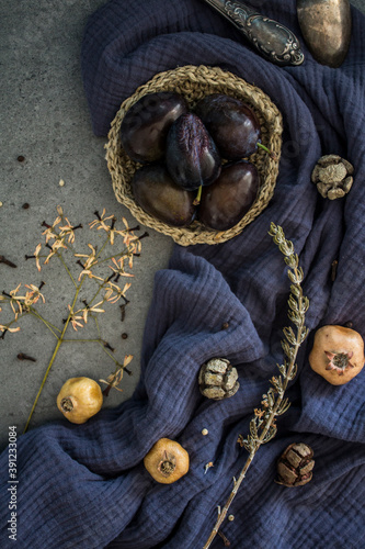 Simple composition still life with dried fruits, flowers and herbs. Autumn mood photo. Blue textured fabric background. 