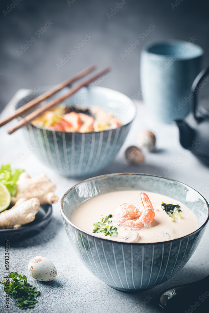 Tom Yum Kung soup, a Thai traditional spicy prawn soup in a bowl on gray background Tom Yum Kung soup, a Thai traditional spicy prawn soup in a bowl on gray background