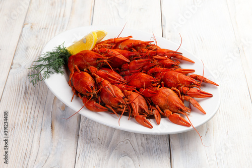Boiled crayfish in a plate on a light background.