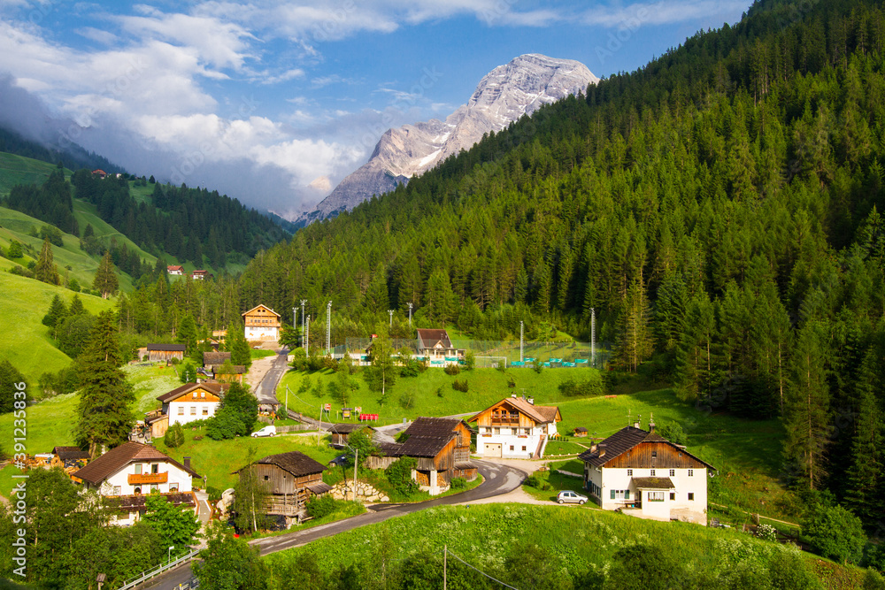 beautiful village in the valley with blue sky and mountains in background, italy, dolomites
