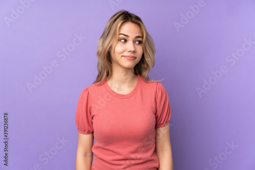 Teenager Russian girl isolated on purple background making doubts gesture looking side