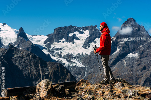 A man with Nordic walking sticks in the mountains. A man traveling in the Caucasus. Mountain sports. Mountain tourism. Walking tour. The journey to the mountains. Nordic walking among the mountains.