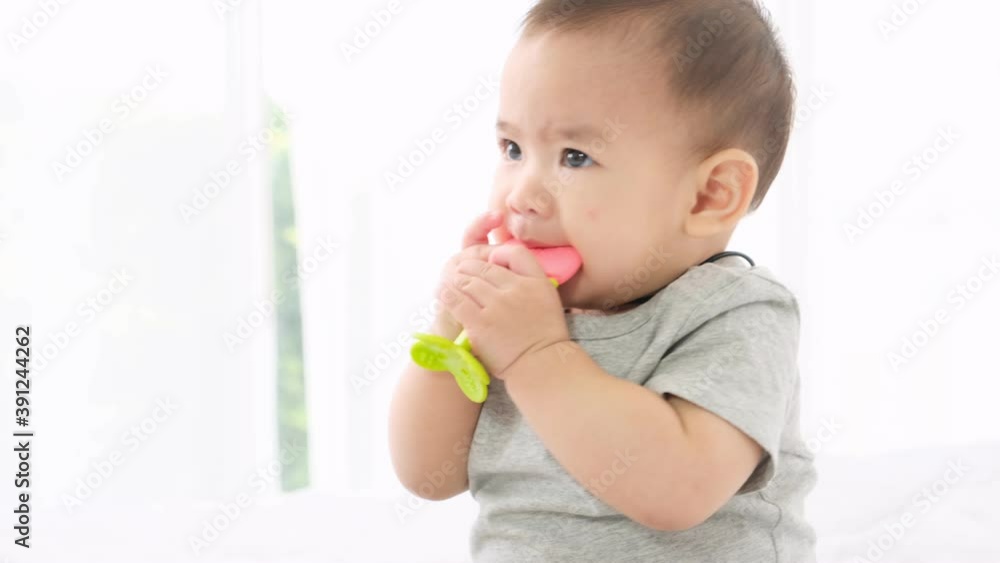 Asian newborn baby girl hold and chew soft rubber fun because itchy gums from teeth that are growing out. Asian newborn baby girl hold and chew soft rubber fun because itchy gums from teeth that are growing out.