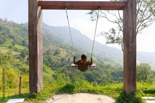 Asian woman relax on swing with the mountain view.