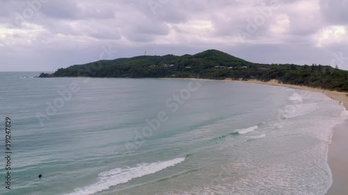 Clear Blue Water Under Cloudy Sky With Lush Green Landscape Coastal Town In Byron Bay, Australia. - Aerial Drone Shot photo