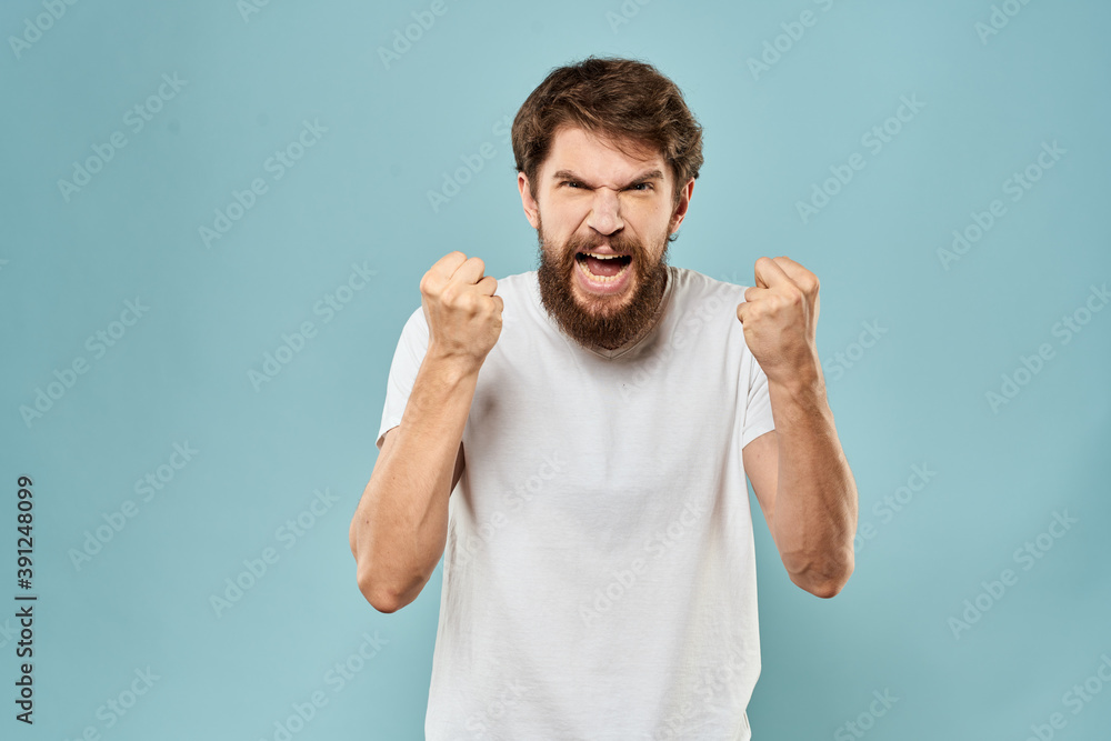 Man gestures with his hands emotions displeasure white t-shirt blue background Man gestures with his hands emotions displeasure white t-shirt blue background