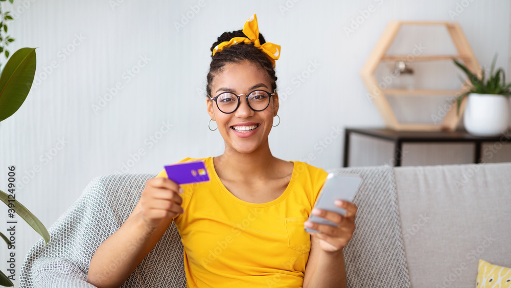 Black lady holding smartphone and credit card at home Black lady holding smartphone and credit card at home