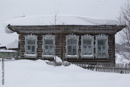 Vintage wooden rural house in Kurlek village, Tomsk region, Russia. Russian snowy winter, snow. Cold season in Siberia. Siberian nature, architecture. Snowdrift photo