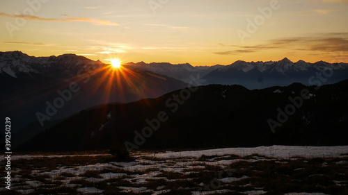 Sun setting beautifully behind rugged mountain ranges in late fall (BC, Canada).