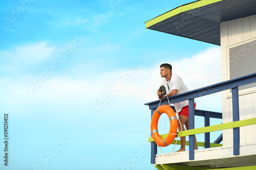 Photos Male lifeguard with binocular on watch tower against blue sky