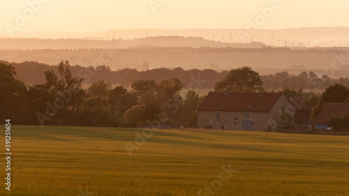 Countryside landscape of rolling hills, old farm houses, all bathed in yellow sunlight (Saxony, Germany).