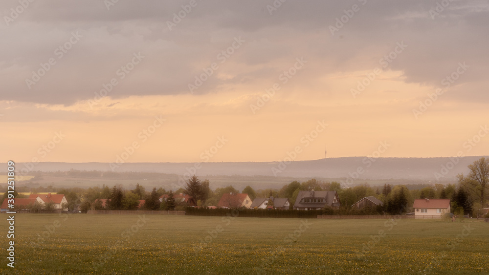 Countryside landscape of rolling hills, old farm, houses, all bathed in yellow sunlight (Germany).