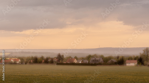 Countryside landscape of rolling hills, old farm, houses, all bathed in yellow sunlight (Germany).