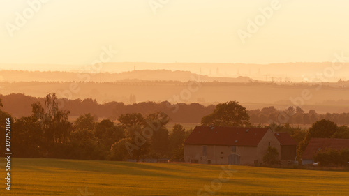 Countrside landscape of rolling hills, old farm houses, all bathed in yellow sunlight (Germany).